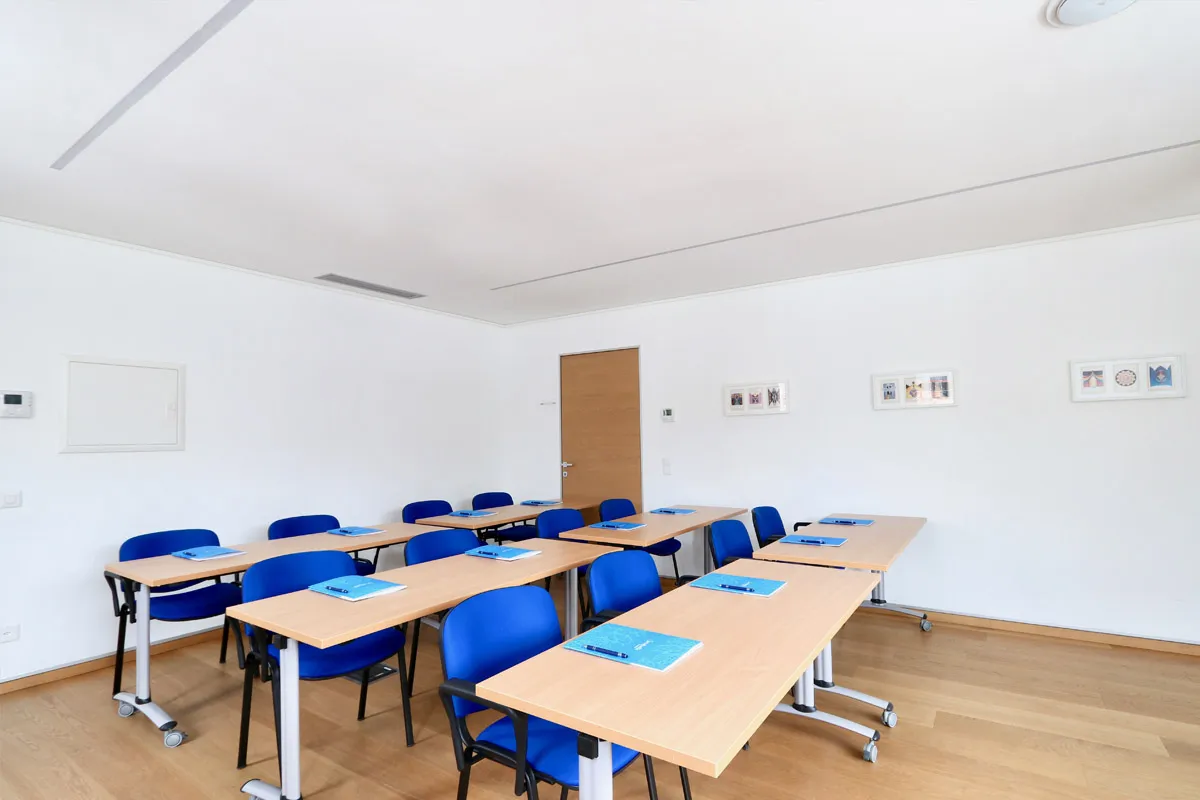 Sala Mimosa allestita ad aula con banchi e sedie blu